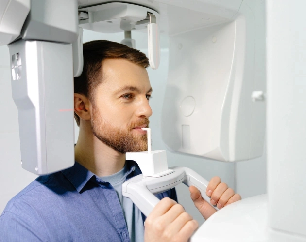 Man operating dental X-ray machine in modern clinical setting