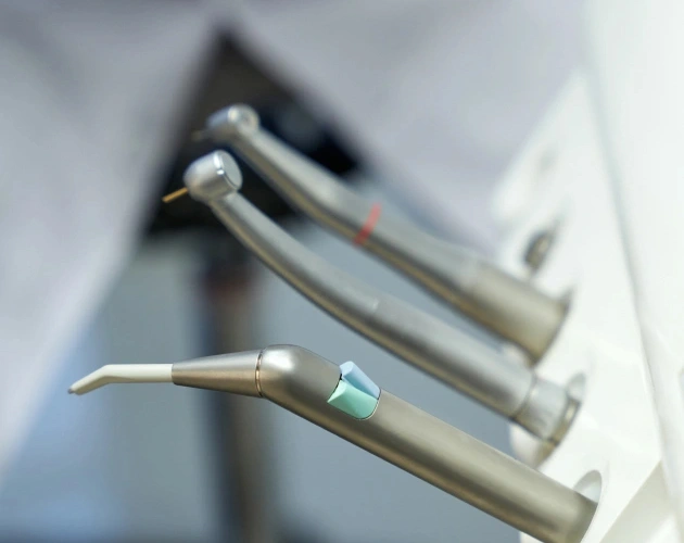 Dental instruments including mirrors and explorers arranged on a white tray in clinical setting.