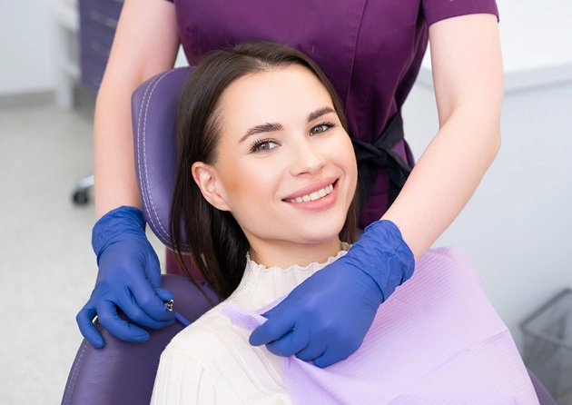 Dental professional in blue gloves examining patient in clinical treatment chair.