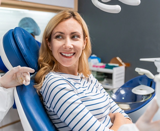 Woman smiling in dental chair wearing striped shirt at periodontal office