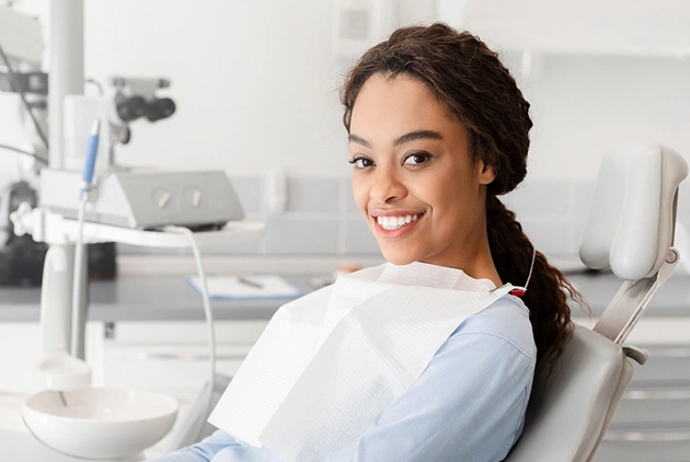 Female patient smiling in dental chair at periodontal practice office.