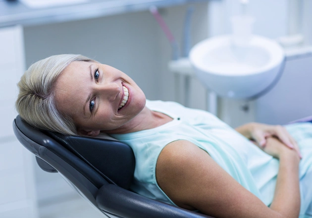 Patient smiling in dental chair during examination at periodontal and implant practice.