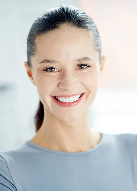 Professional woman smiling at camera in bright clinical setting for dental practice.