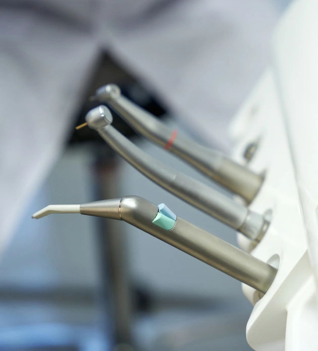 Dental instruments displayed in periodontal office setting, including handpieces and specialized tools.