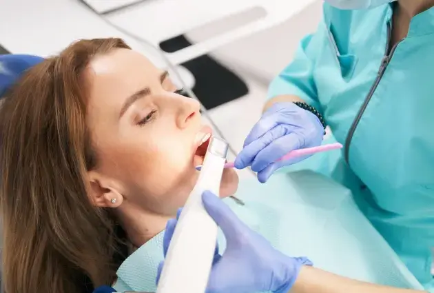Dentist using intraoral camera to examine patient's teeth during dental procedure.