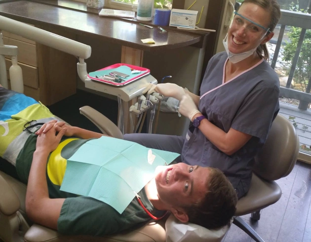 Dentist examining patient in dental chair at periodontics and implants office.