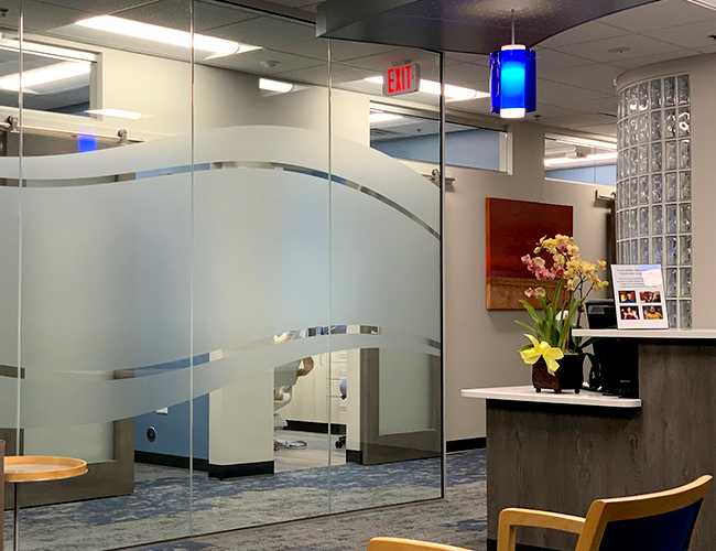 Modern dental office reception area with frosted glass partitions and contemporary furniture.