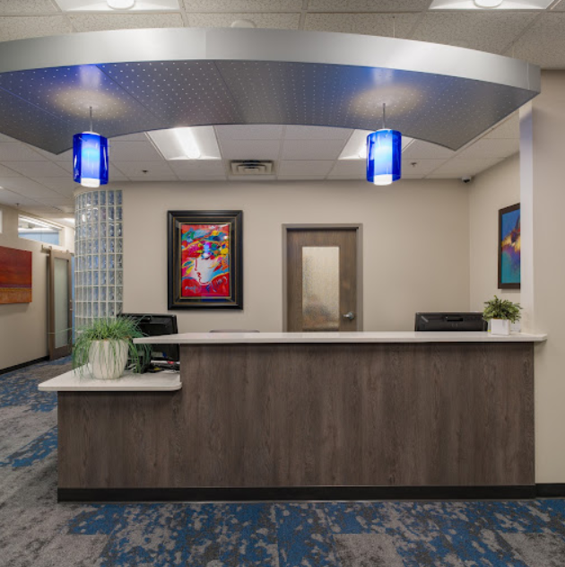 Modern dental office reception area with curved desk, blue accent lighting, and contemporary decor.