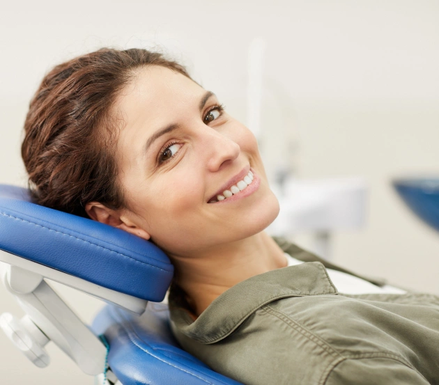 Woman relaxing in dental chair at periodontal office, smiling contentedly during appointment.