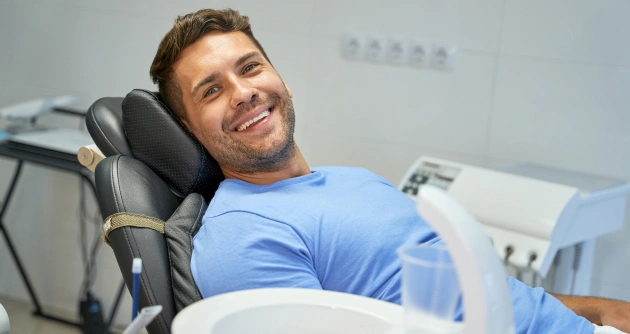 Man in blue shirt relaxing in dental chair at periodontal office during treatment.