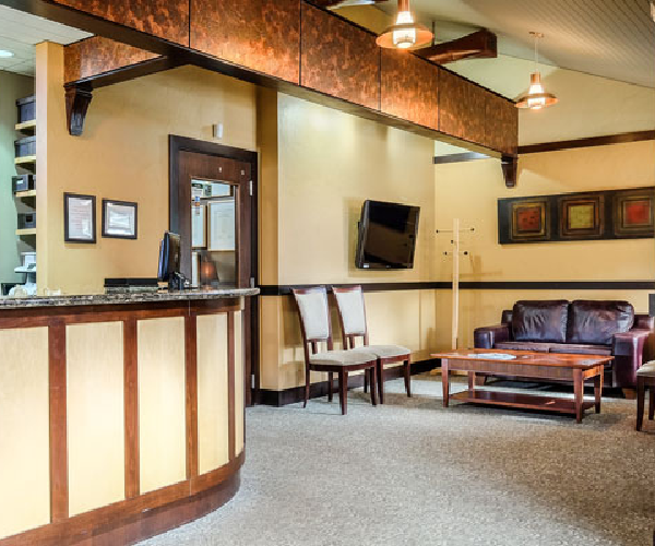 Modern dental office reception area with wooden accents, seating area, and professional décor.