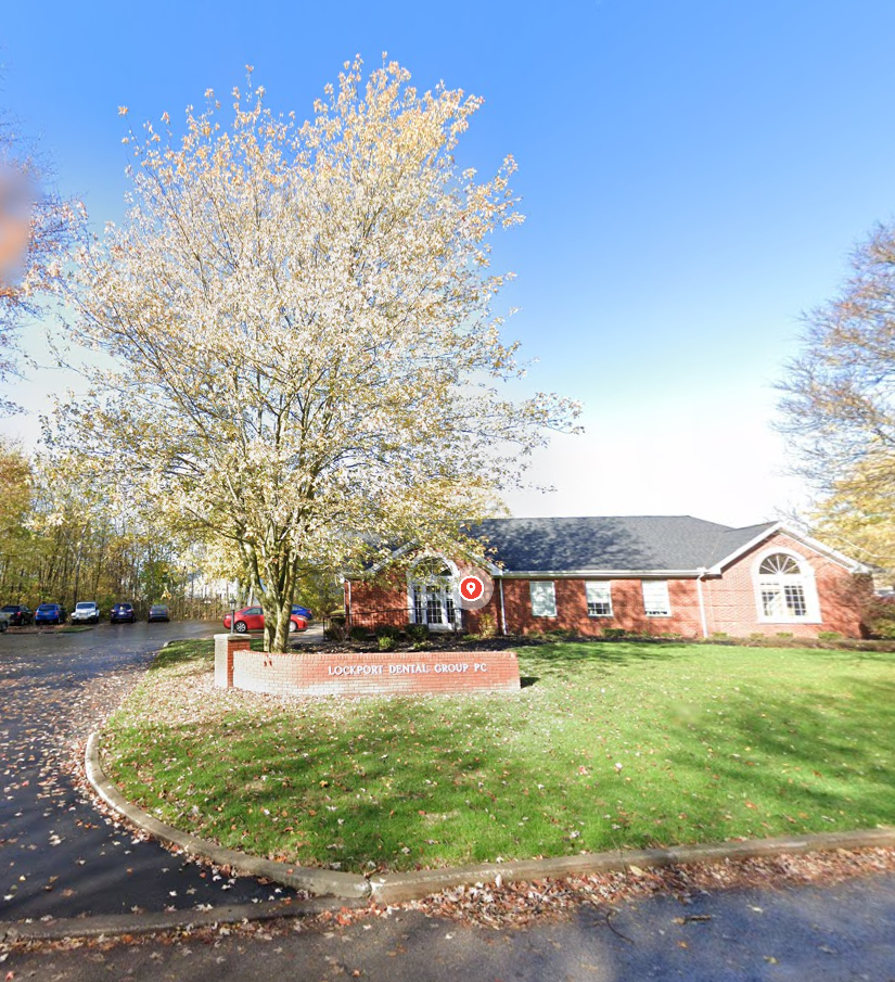 Red brick suburban home with blooming tree and manicured lawn in spring.