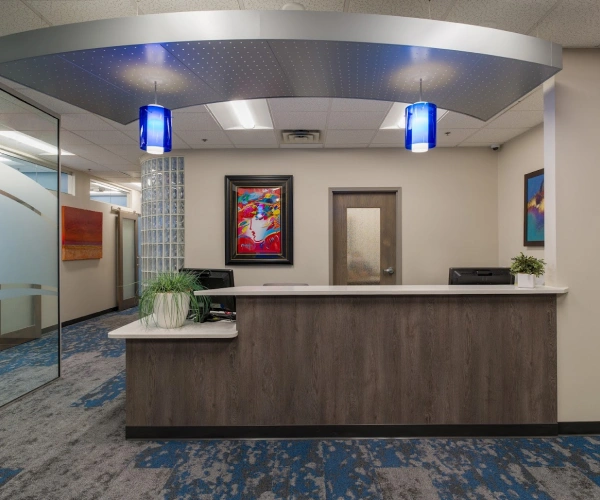 Modern dental office reception area with curved desk, blue accent lighting, and contemporary decor.
