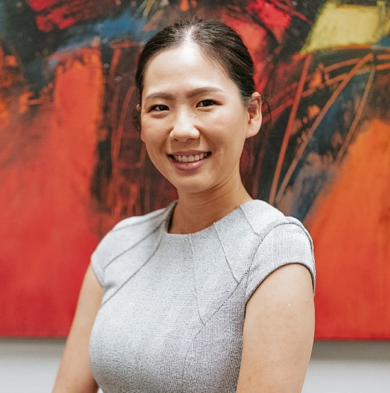 Professional woman smiling at camera in front of colorful abstract artwork in dental office.